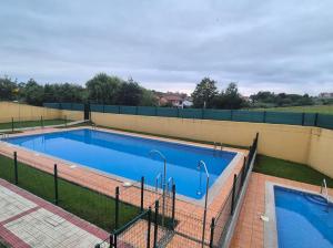 a swimming pool with blue water and a fence at Capricho de Rovacías in Comillas