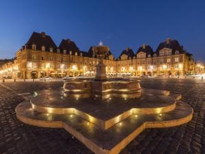 a fountain in front of a large building at night at Love Room avec Jacuzzi Privatif Loft Sensation Romantique in Renwez