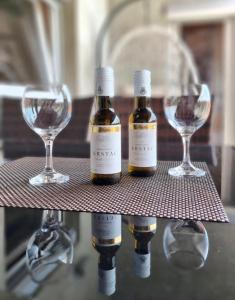three bottles of wine on a shelf with glasses at Apartman Avram in Kotor-Varoš