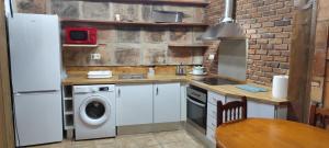a kitchen with a washer and dryer next to a brick wall at Casa Sabinar in Navajas +8 photos