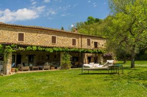 a large stone building with chairs and a table in a yard at Le Bumbarelle in Tavoleto