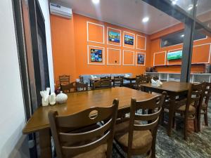 a dining room with tables and chairs and orange walls at Will Hotel in Baku