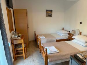 a room with three beds and a table and a chair at ZOGRAFOS 2 in Haraki