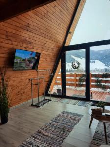 a living room with a flat screen tv on a wooden wall at Cozy A-Frame Cabins in Bucovina in Şarul Dornei +16 photos