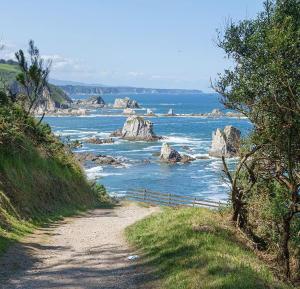 a dirt road next to the ocean with rocks at Villa Playa del Silencio in Castañeras