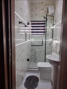 a white bathroom with a toilet and a sink at OYO Serviced Apartment in Egbe