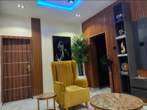 a living room with a yellow chair and a table at OYO Serviced Apartment in Egbe