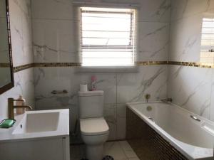 a bathroom with a toilet and a tub and a sink at Private Secure house in Alberton in Alberton