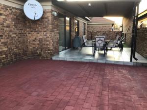 a patio with chairs and a clock on a brick wall at Private Secure house in Alberton in Alberton +2 photos