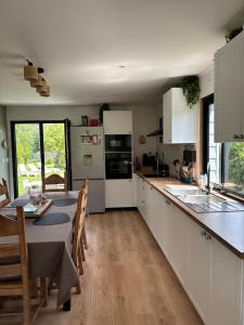 a kitchen with white cabinets and a table and a table and chairs at Maison La Béa-titude in Serques