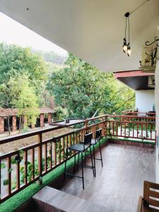 a balcony with chairs and a view of the forest at Mountainview Paradise - Cozy 1bhk amidst mountains in Karjat