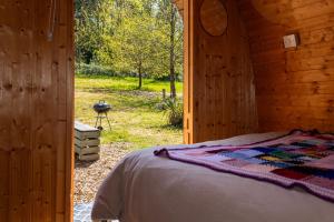 a bedroom with a bed in a wooden cabin at Battle Pods and Bells Glamping in Battle