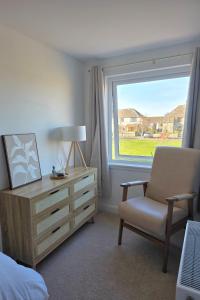 a bedroom with a chair and a dresser and a window at Coastal Cottage NC500 in Castletown