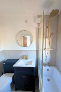 a bathroom with a sink and a tub and a mirror at Coastal Cottage NC500 in Castletown