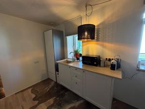 a kitchen with white cabinets and a counter with a microwave at Viesu māja Gulbji in Bigauņciems