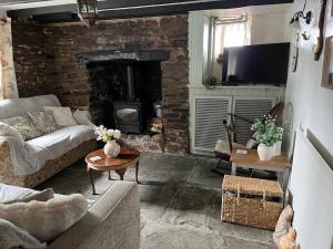 a living room with a couch and a stone fireplace at The Eliot Cottage in South Petherwin