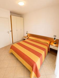 a bedroom with a orange and orange striped bed at RESIDENCE STEFANIA - AGENZIA COCAL in Caorle