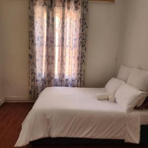 a bedroom with a white bed with a window at S-and Kasa Guest House in Pietermaritzburg