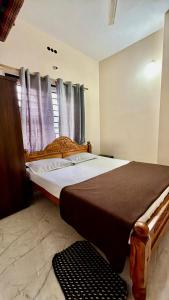 a bedroom with a large bed and a window at Shriyaamvitha Homestays in Madikeri