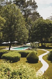 a garden with a swimming pool and bushes and trees at Château de Maraval in Cénac-et-Saint-Julien