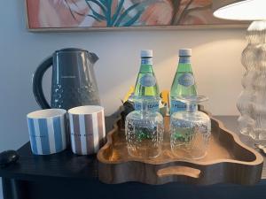 a wooden tray with three bottles and cups on a table at Wisteria House Boutique Stay Marlow in Marlow