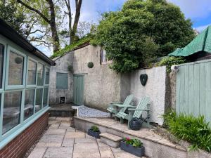 a patio with two chairs and a table next to a house at The Eliot Cottage in South Petherwin