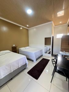 a hotel room with two beds and a desk at Hotel Araújo in Capitão Poço +8 photos