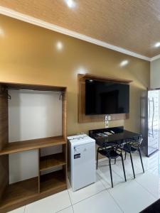 a room with a table and a tv and a small refrigerator at Hotel Araújo in Capitão Poço