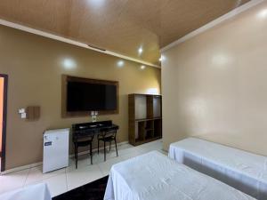 a bedroom with a bed and a tv and a table at Hotel Araújo in Capitão Poço