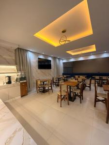 a dining room with tables and chairs and a tv at Hotel Araújo in Capitão Poço