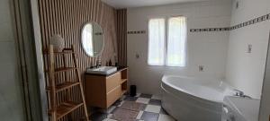 a bathroom with a tub and a sink and a mirror at Berges de la Suippe in Warmeriville