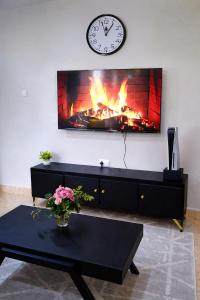 a living room with a fireplace with a clock on the wall at Rosewood Cozy homes in Mbeya