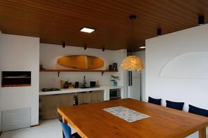 a kitchen and dining room with a wooden table at Artha Home Spa in Governador Celso Ramos