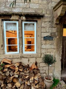 a pile of fire wood next to two windows at Four bedroomed 18th century cosy cottage three miles from Bath City Centre in Batheaston