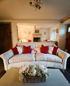 a living room with a white couch with red pillows at Four bedroomed 18th century cosy cottage three miles from Bath City Centre in Batheaston