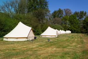 a row of white tents in a field at Battle Pods and Bells Glamping in Battle