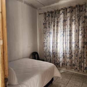 a bedroom with a bed and a window with curtains at S-and Kasa Guest House in Pietermaritzburg +17 photos