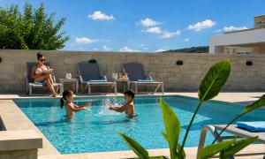 a woman and two children playing in a swimming pool at Marea Villas Heated Pool in Dhrámia