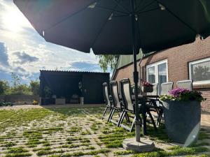 a patio with a table and chairs under an umbrella at Vakantiewoning Op de Woerd in Aalten