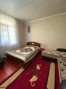 a bedroom with two beds and a red rug at Mta House Racha in K'veda Shavra +15 photos