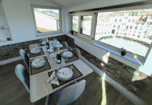 a dining room with a table and two windows at Attico di Cesare Luxury Piazza Anfiteatro Lucca in Lucca