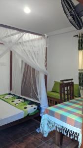 a bedroom with a bed and a chair with a canopy at The Shilpa Villa in Unawatuna