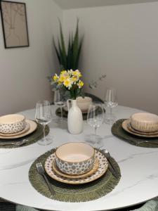 a dining room table with plates and glasses and flowers at Modern Design Apartment Salona I Stylish & Comfortable Solin I Split in Solin