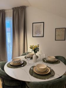 a dining room table with plates and glasses and a vase with flowers at Modern Design Apartment Salona I Stylish & Comfortable Solin I Split in Solin