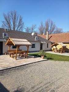 a patio with picnic tables and a house at BB64 Apartmanház in Békéscsaba