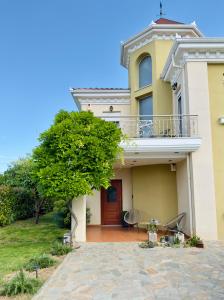 a yellow house with a balcony and a porch at Avgerinos in Makrochórion
