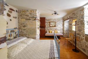 a bedroom with a bed and a stone wall at Next to the Bougainvillea! in Ano Syros