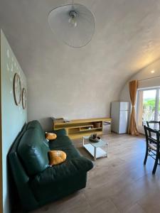 a living room with a green couch and a table at voute atypique 40 m2 in Montaigut-le-Blanc