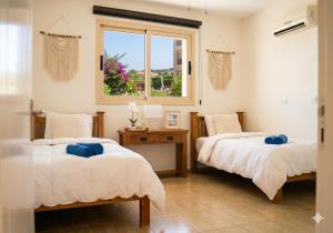 two beds in a room with a window at Sunshine Royal Seacrest- Prime Location Paphos with Pool in Paphos +22 photos