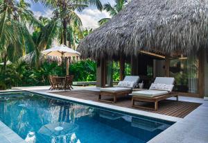 a resort with a swimming pool with chairs and an umbrella at Casa Bambu Tayrona, Los Naranjos in Los Naranjos